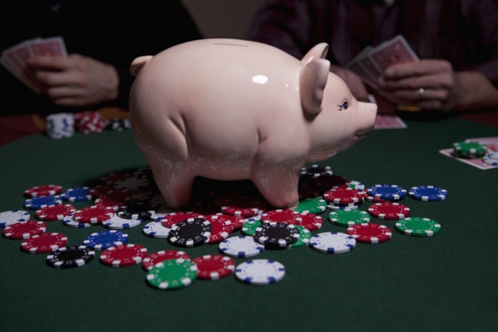 People playing poker with a piggy bank containing the winning prize in the middle of the poker table