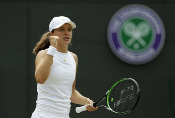 iga swiatek wearing white and holding up fist at wimbledon